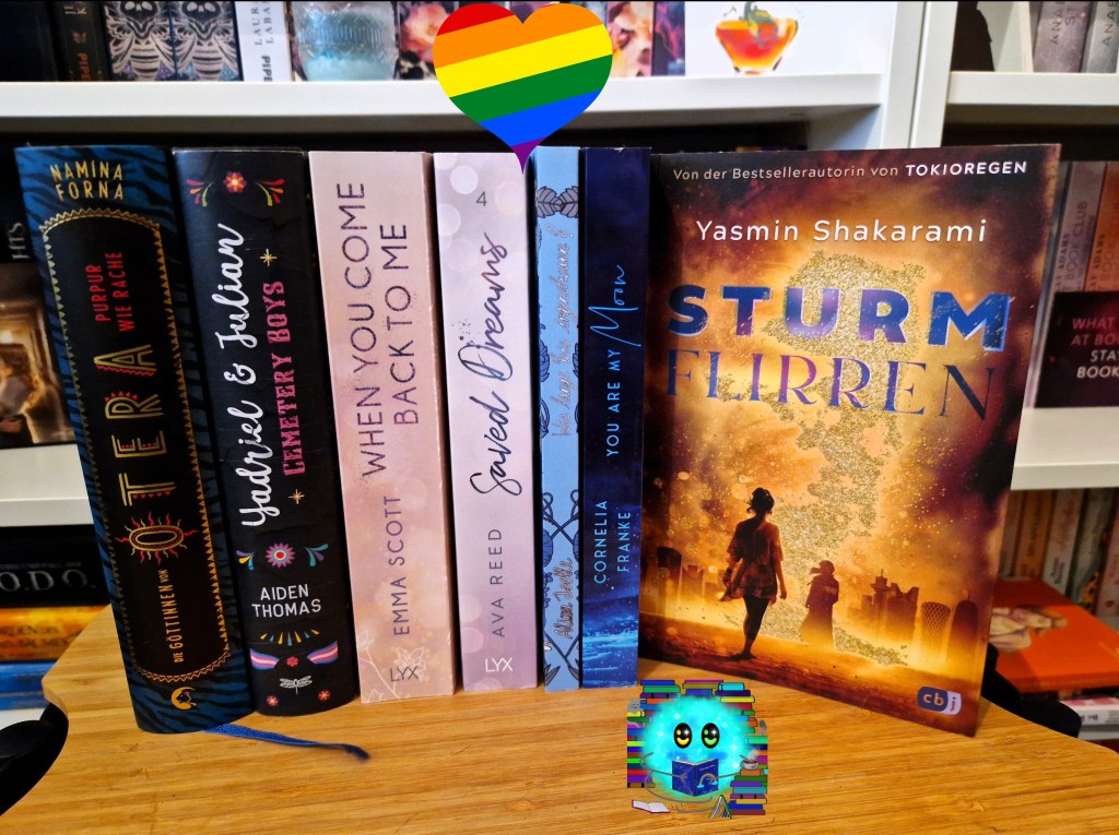 Die im Beitrag erwähnten Bücher arrangiert vor einem Bücherregal mit einem Herz darüber in Regenbogenfarben