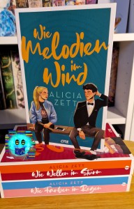 Cover zu Wie Melodien im Wind mit den beiden Protagonist*innen, die nebeneinander auf einer Bank sitzen und Musik hören